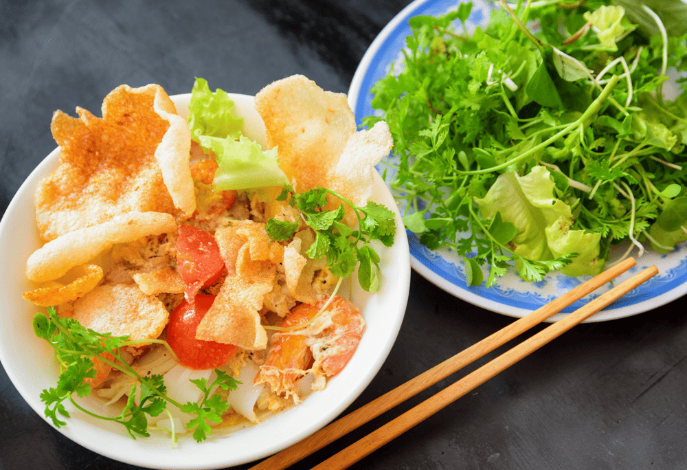 Illustration of Mi Quang at Co Anh, always serving bowls full of toppings and fresh herbs (Source: Internet)